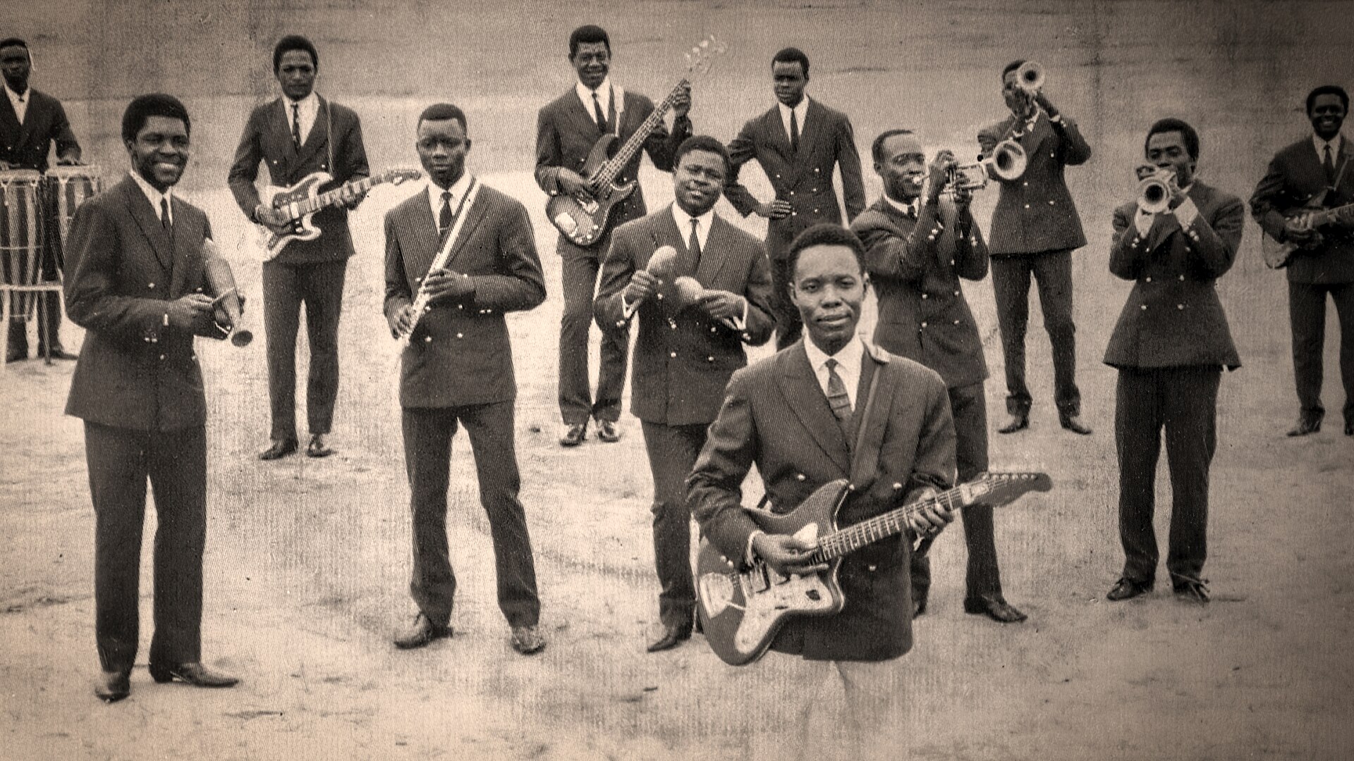 Photographie d’archive : un orchestre de rumba congolaise et ses instruments à cordes, cuivres et percussions.